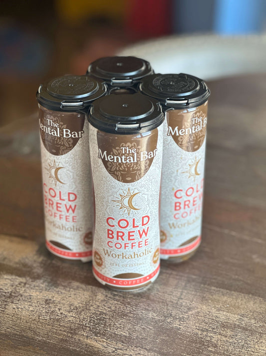 Four cans of The Mental Bar Cold Brew Coffee, each labeled 'Workaholic', are arranged on a surface.