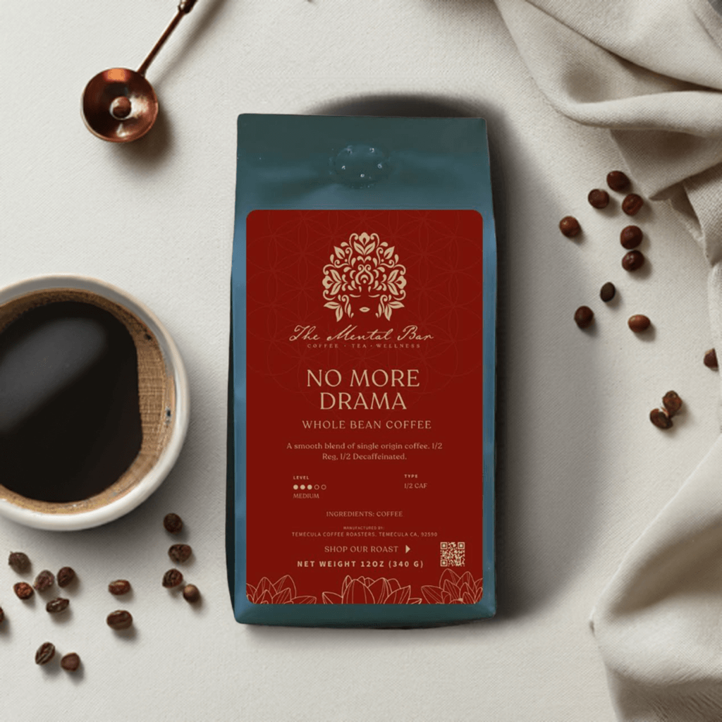 A pack of 'No More Drama' whole bean coffee by The Mental Bar, with a cup of coffee and coffee beans scattered on the surface behind it.